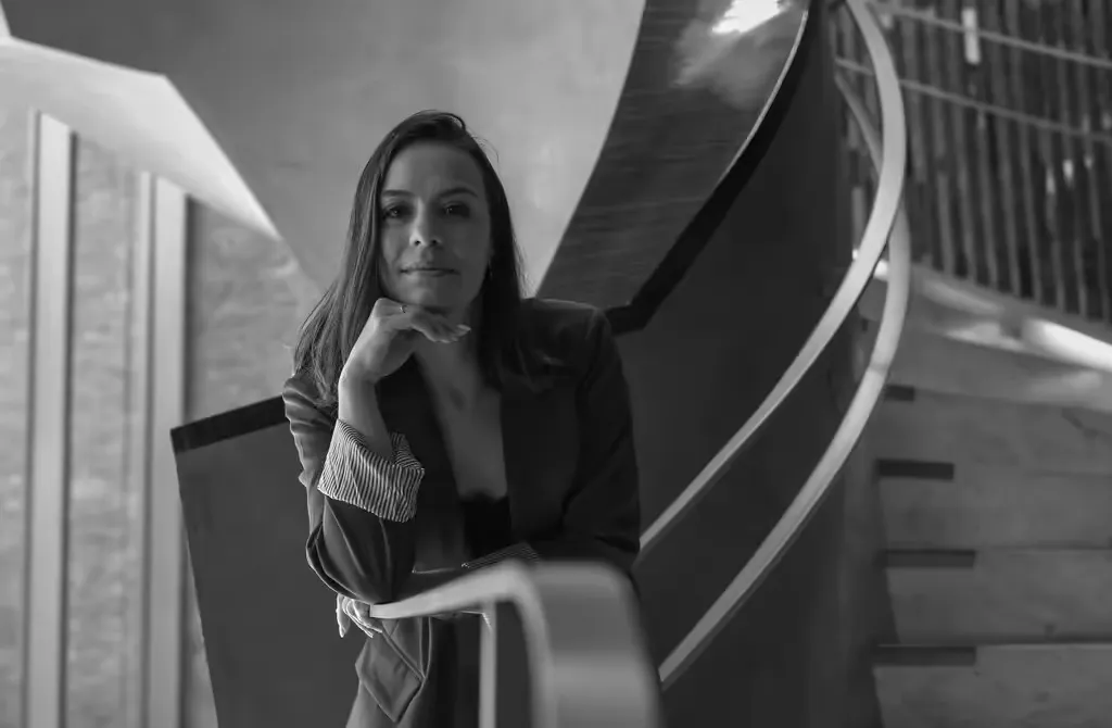 Gabriela M. Pesce apoiada em uma escada, em preto e branco