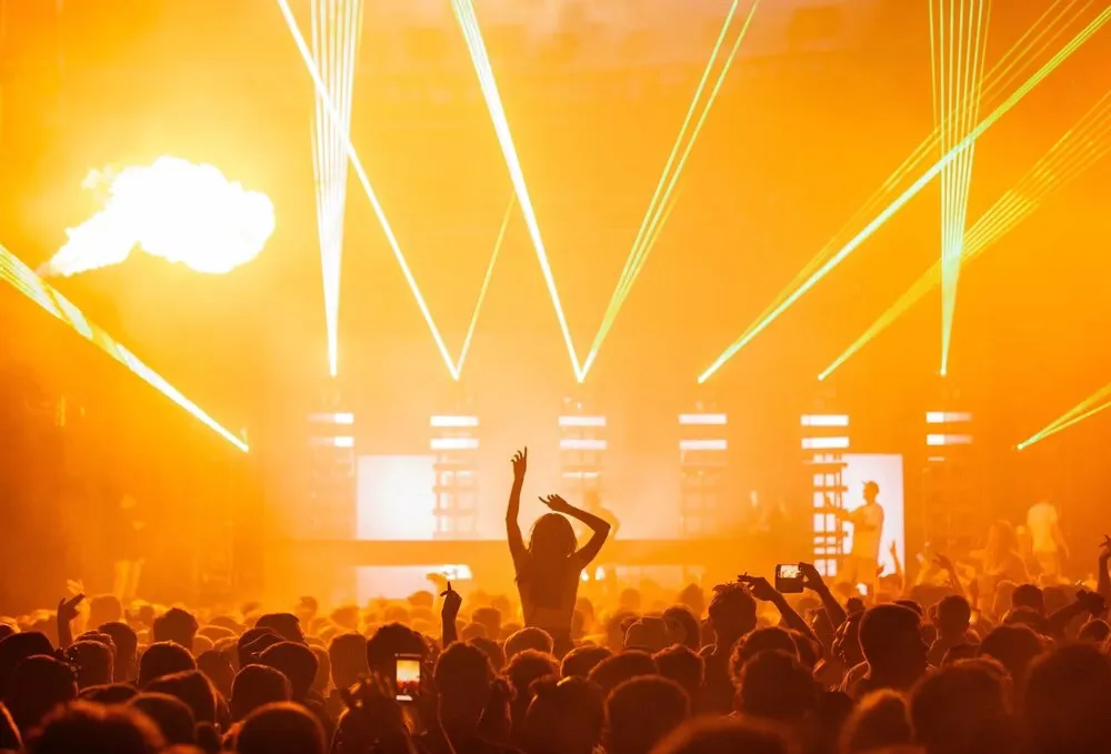 Público em um show com luzes e lasers amarelos