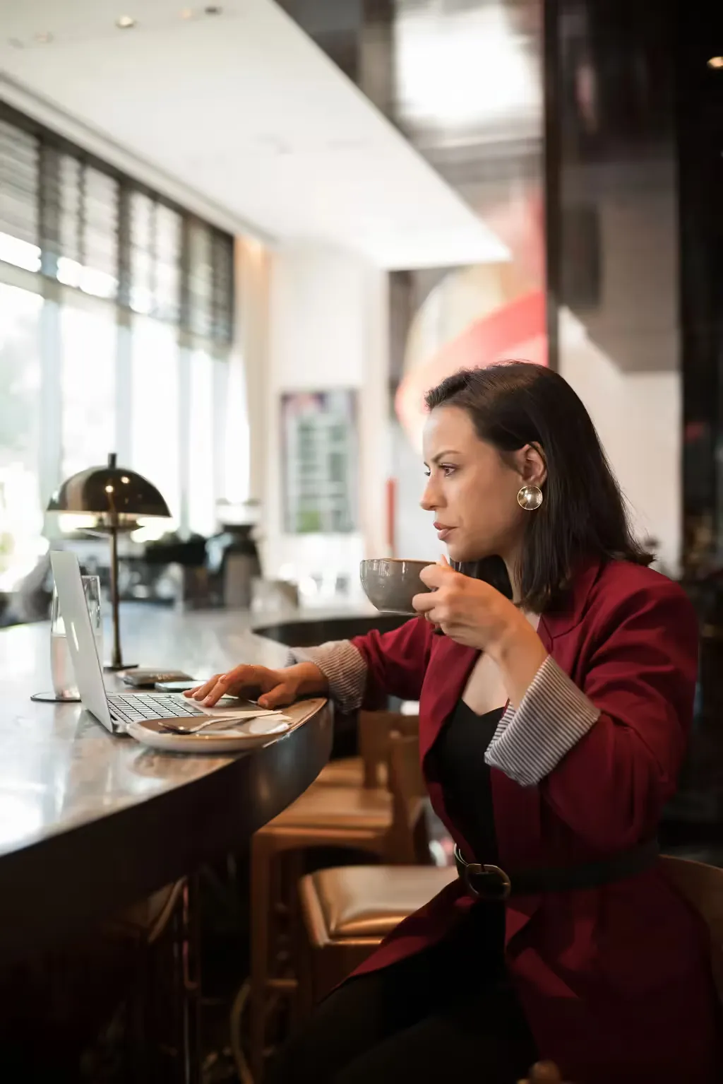 Gabriela M. Pesce trabalhando no notebook em um café