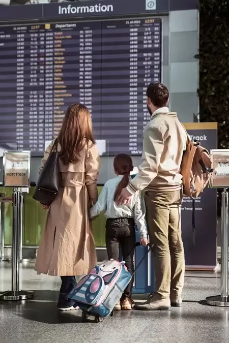 Casal com mala em frente ao painel de voos de um aeroporto